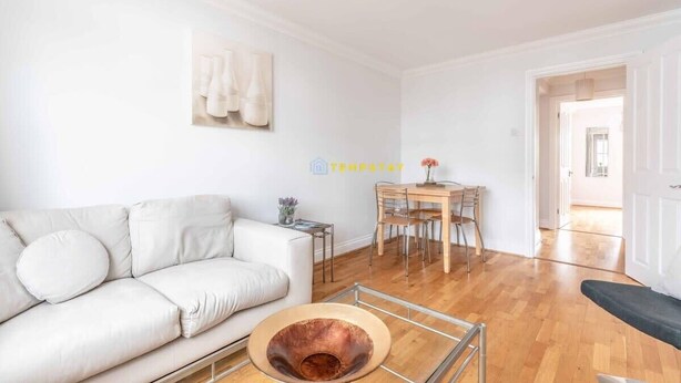 A living room with a white sofa, a coffee table, and a dining area with a wooden table and chairs. - 2 Bed Apt| Parking| Central Windsor By Tempstay (Windsor)