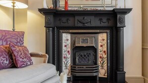 A fireplace with intricate designs, a sofa with patterned cushions, and a lamp. - Luxury Home- Parking- Walk 2 Sights By Tempstay (Windsor)