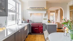A modern kitchen with a red stove, white cabinetry, and a sign above the stove that reads 'Windsor Castle SL4'. - Luxury Home- Parking- Walk 2 Sights By Tempstay (Windsor)