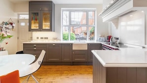 A modern kitchen with a large window, dark cabinetry, and a white countertop. - Luxury Home- Parking- Walk 2 Sights By Tempstay (Windsor)