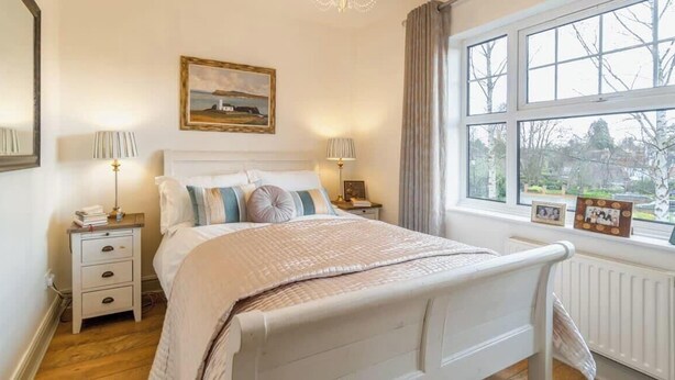 A bedroom with a bed, bedside tables, a window with a view, and a painting on the wall. - Luxury Home- Parking- Walk 2 Sights By Tempstay (Windsor)