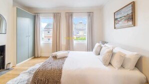 Habitación de hotel con una cama grande, vistas de la ciudad a través de las ventanas, un cuadro en la pared y un armario.