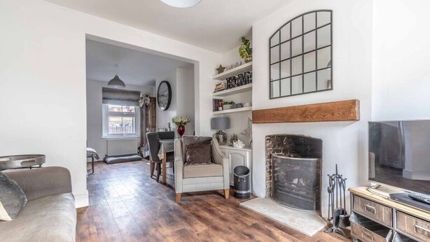 A living room with a fireplace, a television, and a dining area with a table and chairs. - Stunning Victorian Cottage in Windsor By Tempstay (Windsor)