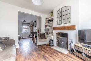 A living room with a fireplace, a television, and a dining area with a table and chairs.