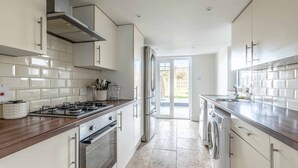 A modern kitchen with white cabinets, stainless steel appliances, and a wooden countertop. - Stunning Victorian Cottage in Windsor By Tempstay (Windsor)