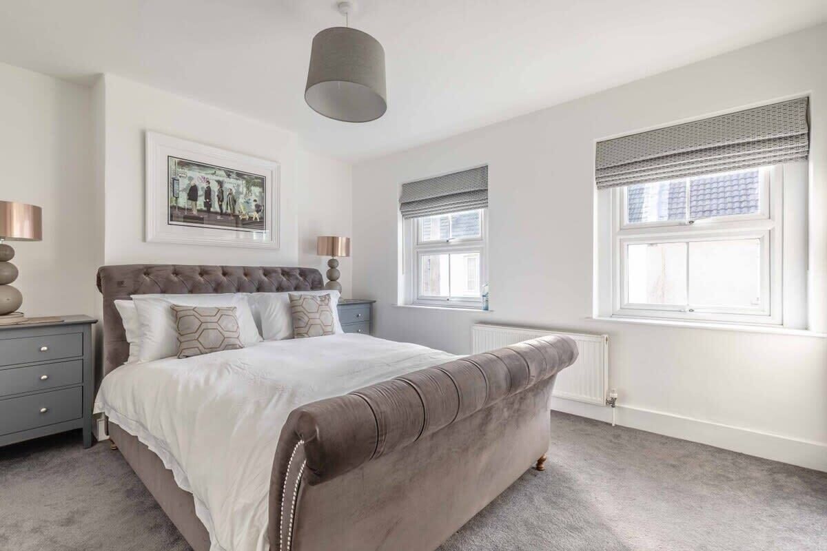 A bedroom with a large bed, bedside tables, a radiator, and a window with blinds.