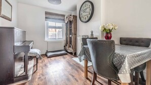 A dining area with a table, chairs, a clock, and a window. - Stunning Victorian Cottage in Windsor By Tempstay (Windsor)