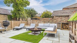 Ein Garten mit Feuerstelle, Sitzgelegenheit und Grill.