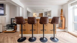 Eine moderne Küche mit Bar und vier Barhocker, daneben eine große Weinflasche.