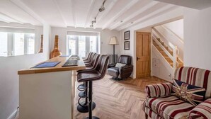 Ein modernes Interieur mit Barbereich, Ledersesseln, einer Couch mit Union-Jack-Muster und einer Treppe.
