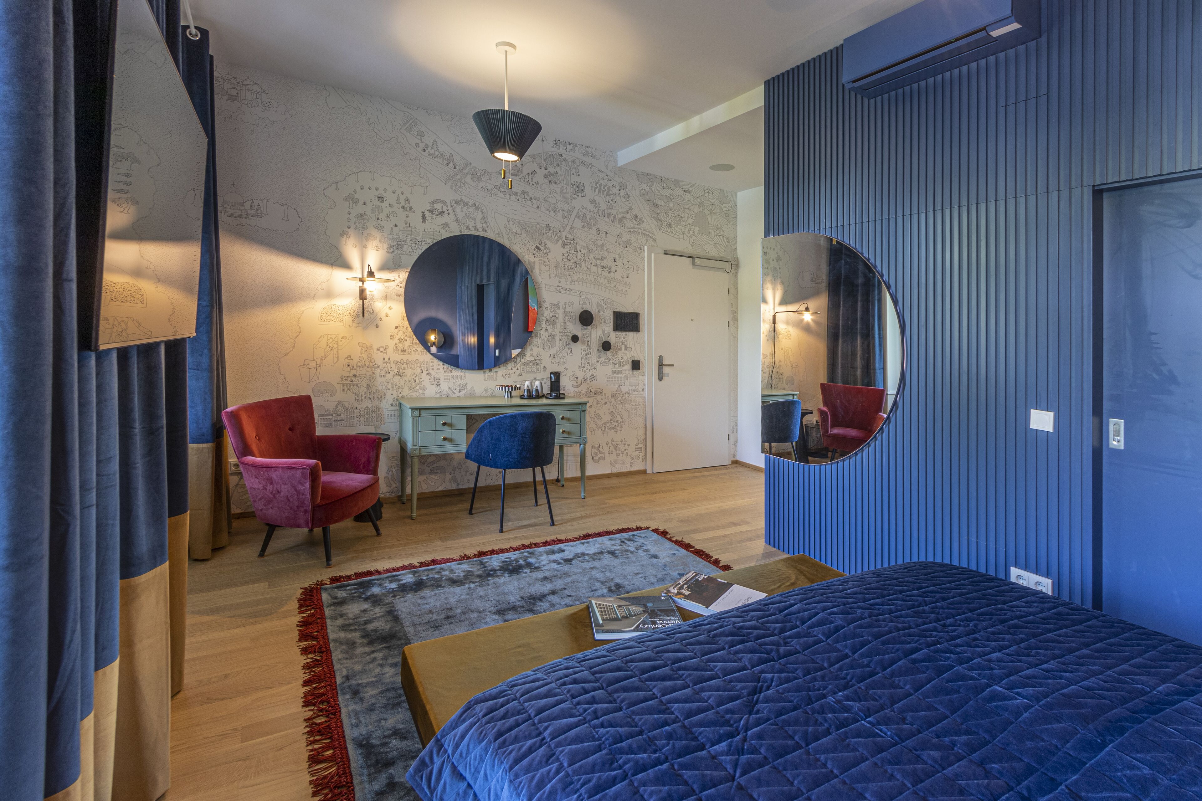 Un dormitorio con cama, escritorio, silla, cómoda y dos espejos.