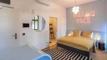 A modern bedroom with a bed, bedside table, and a neon sign on the wall.