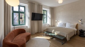 Une chambre moderne avec un lit, une télévision, un canapé et une fenêtre avec des rideaux.