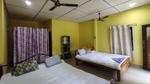 Een kamer met twee enkele bedden, een plafondventilator, een spiegel en gordijnen.