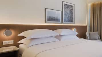 A neatly made bed with white linens, a bedside table with a lamp, and two framed pictures on the wall.
