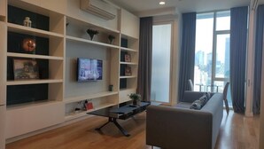 Ein modernes Wohnzimmer mit einer Couch, einem Fernseher und Regalen.