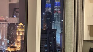 Der Petronas Towers bei Nacht mit Spiegelungen in einem Fenster.