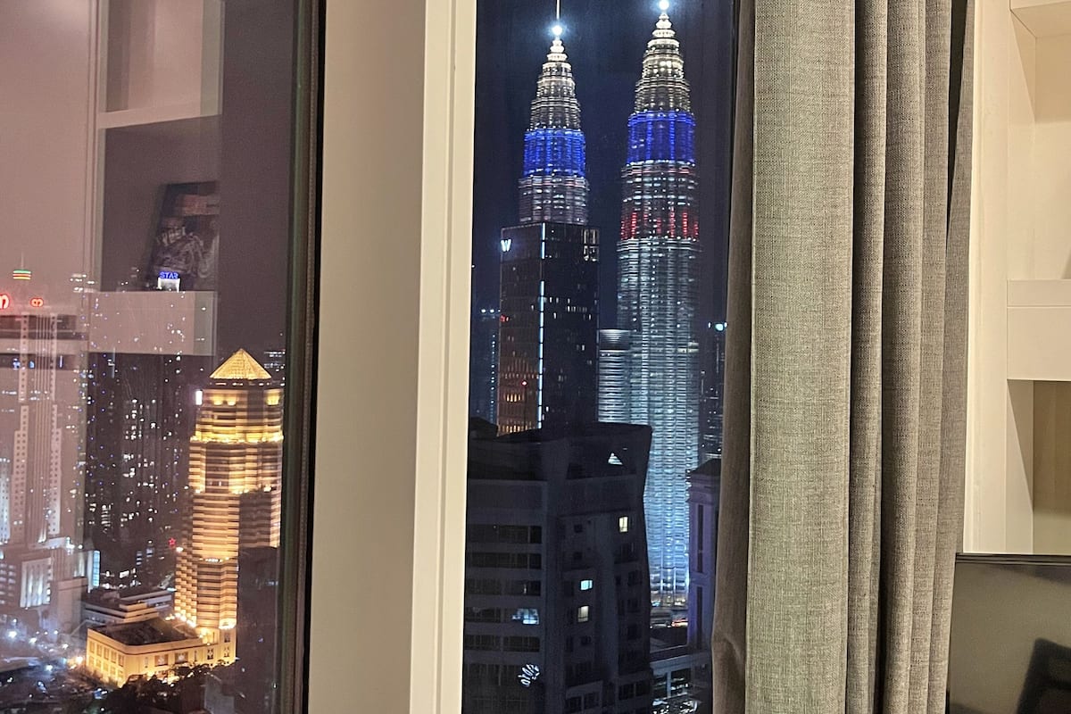 A view of the Petronas Twin Towers at night with reflections in a window.