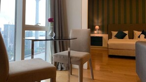 Ein Hotelzimmer mit Blick auf einen Turm, ein runder Tisch mit einer Vase, eine Couch und eine gestreifte Wand.