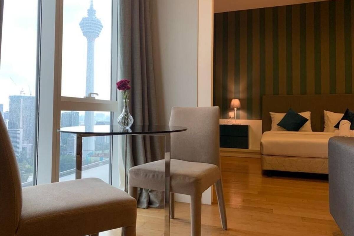 A hotel room with a view of a tower, a round table with a vase, a sofa, and a striped wall.