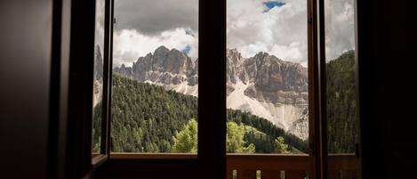 A room with a large window offering a view of a mountainous landscape.