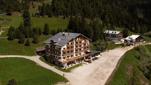 A multi-story hotel with a ski lift in the background, surrounded by forested hills. - PLOSE Parkhotel & Residence (Bressanone)