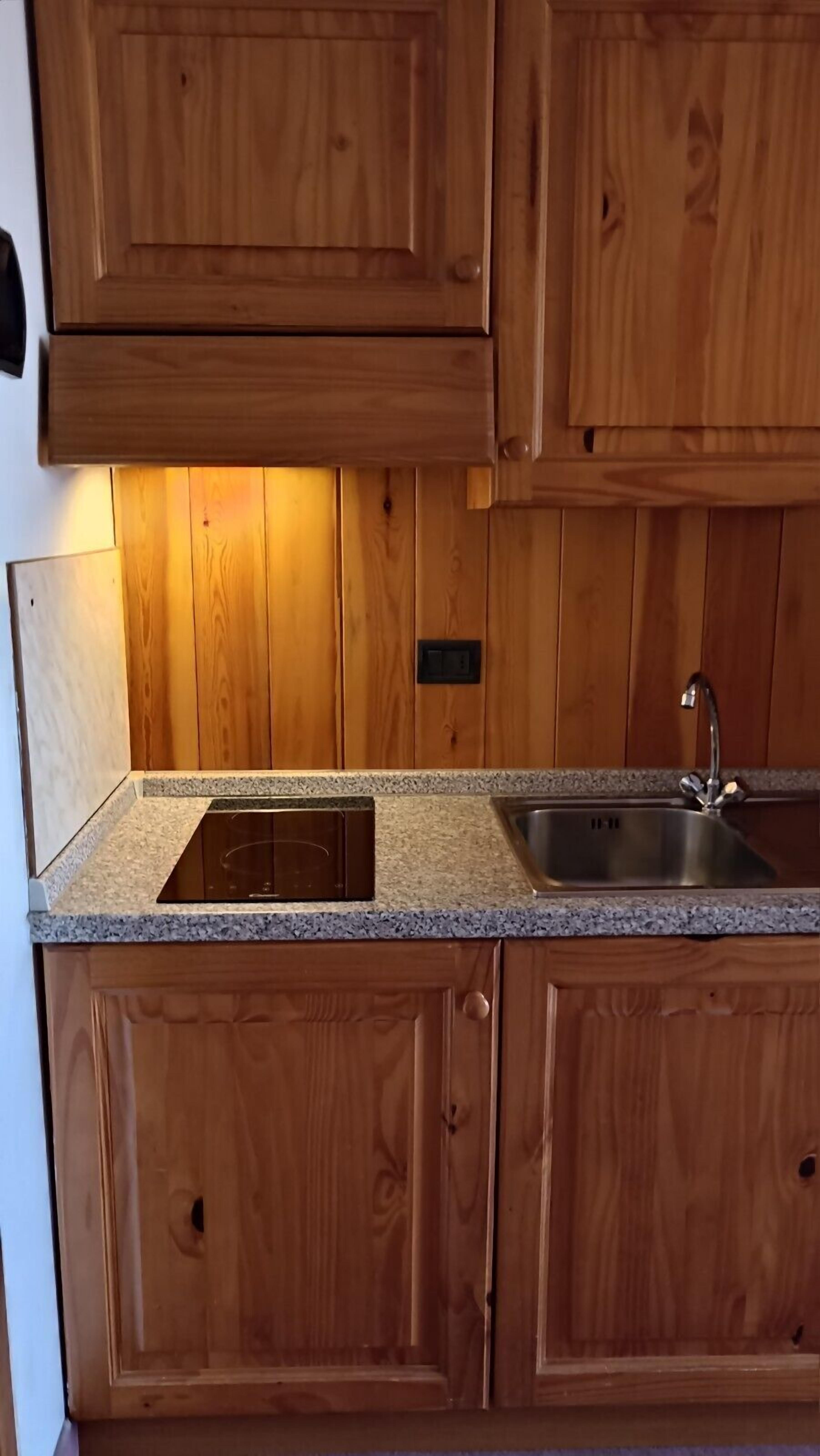 Eine Küche mit Holzausstattung, einer Granit Arbeitsplatte und einem Edelstahl-Spülbecken.