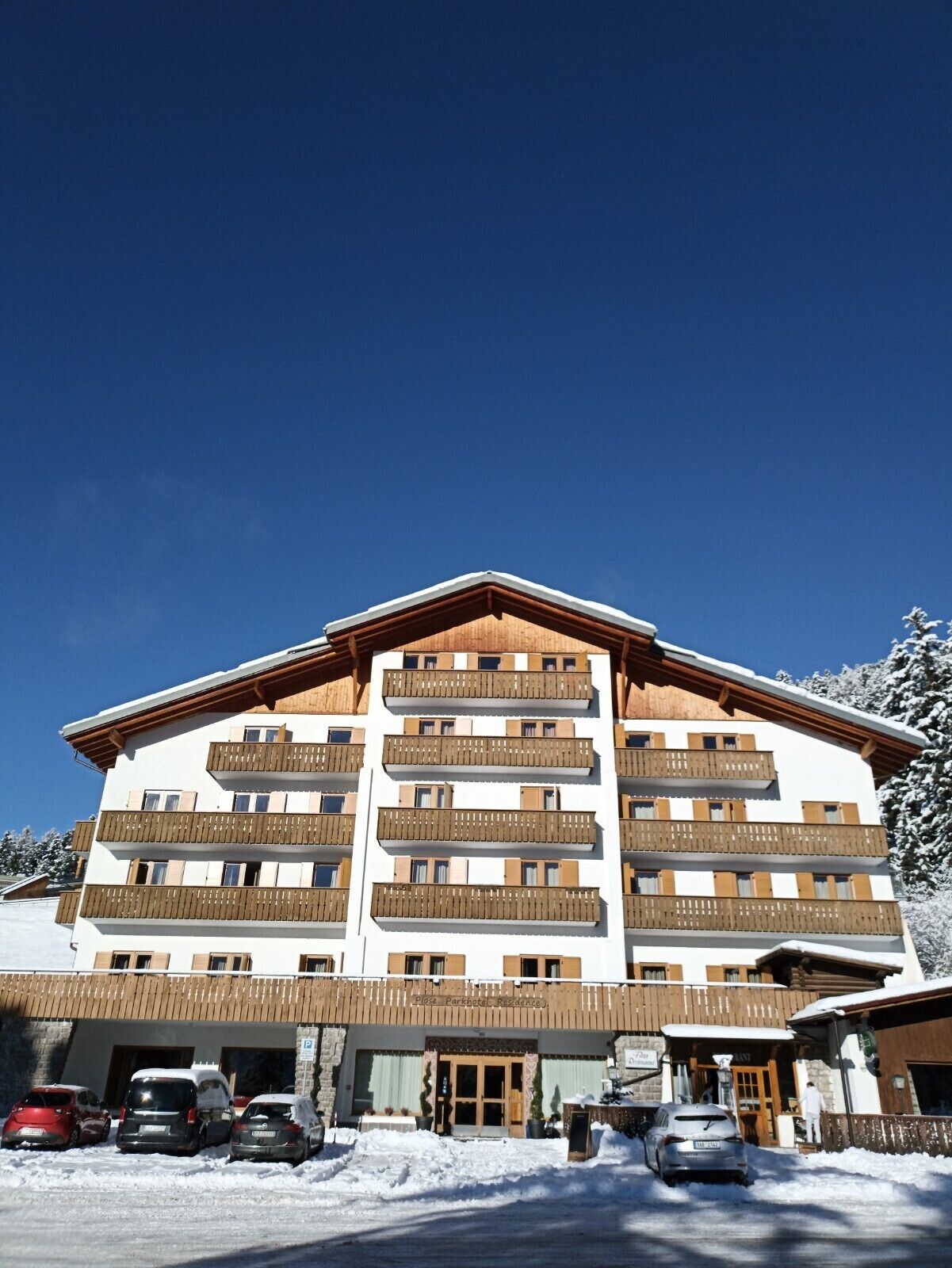 A multi-story hotel with balconies, a wooden facade, and a snow-covered environment.