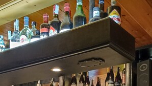 A bar area with shelves of liquor bottles, glasses, and a jar of cookies. - PLOSE Parkhotel & Residence (Bressanone)