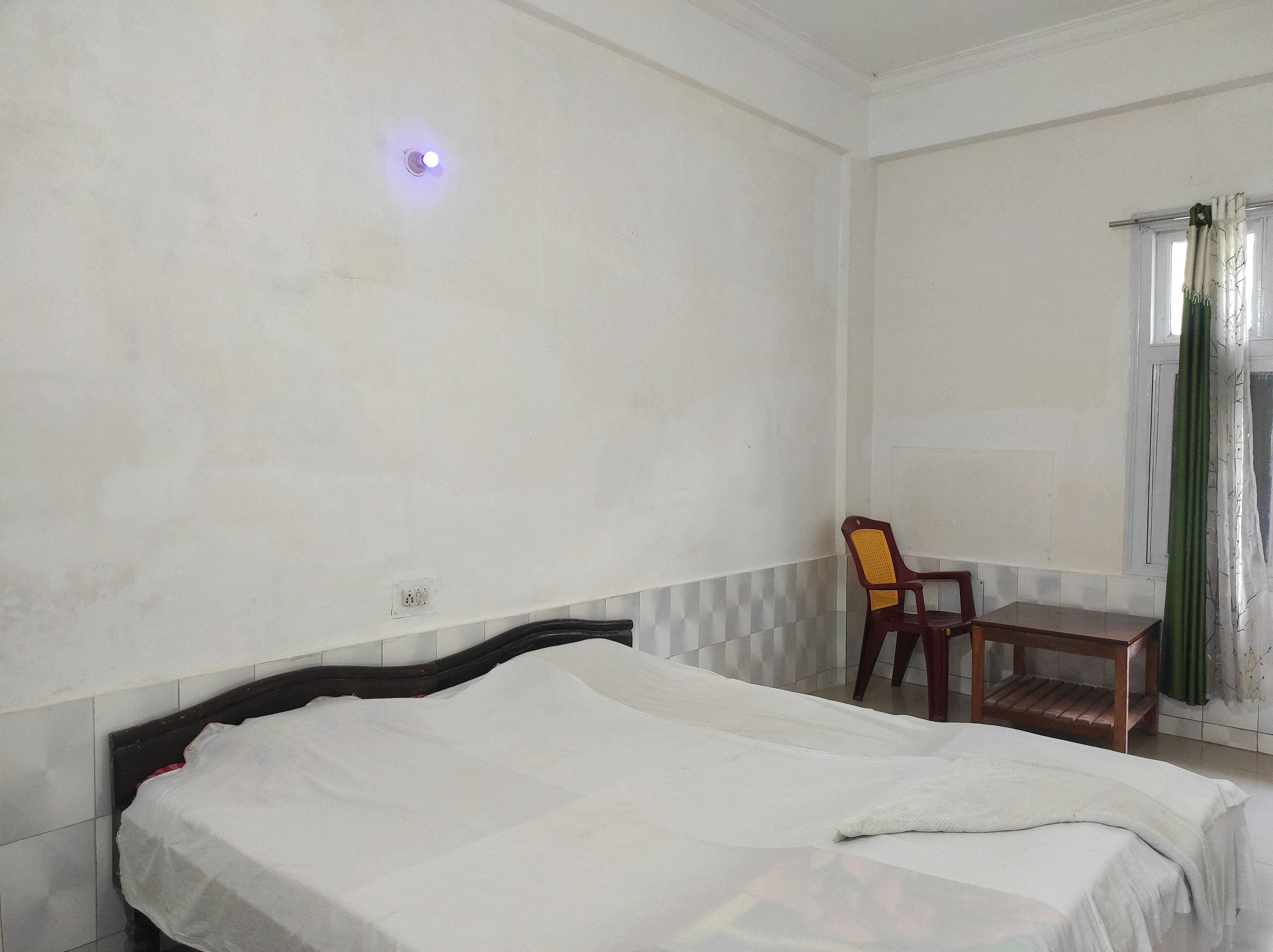 Une chambre à coucher avec un lit, une chaise et une fenêtre avec des rideaux.