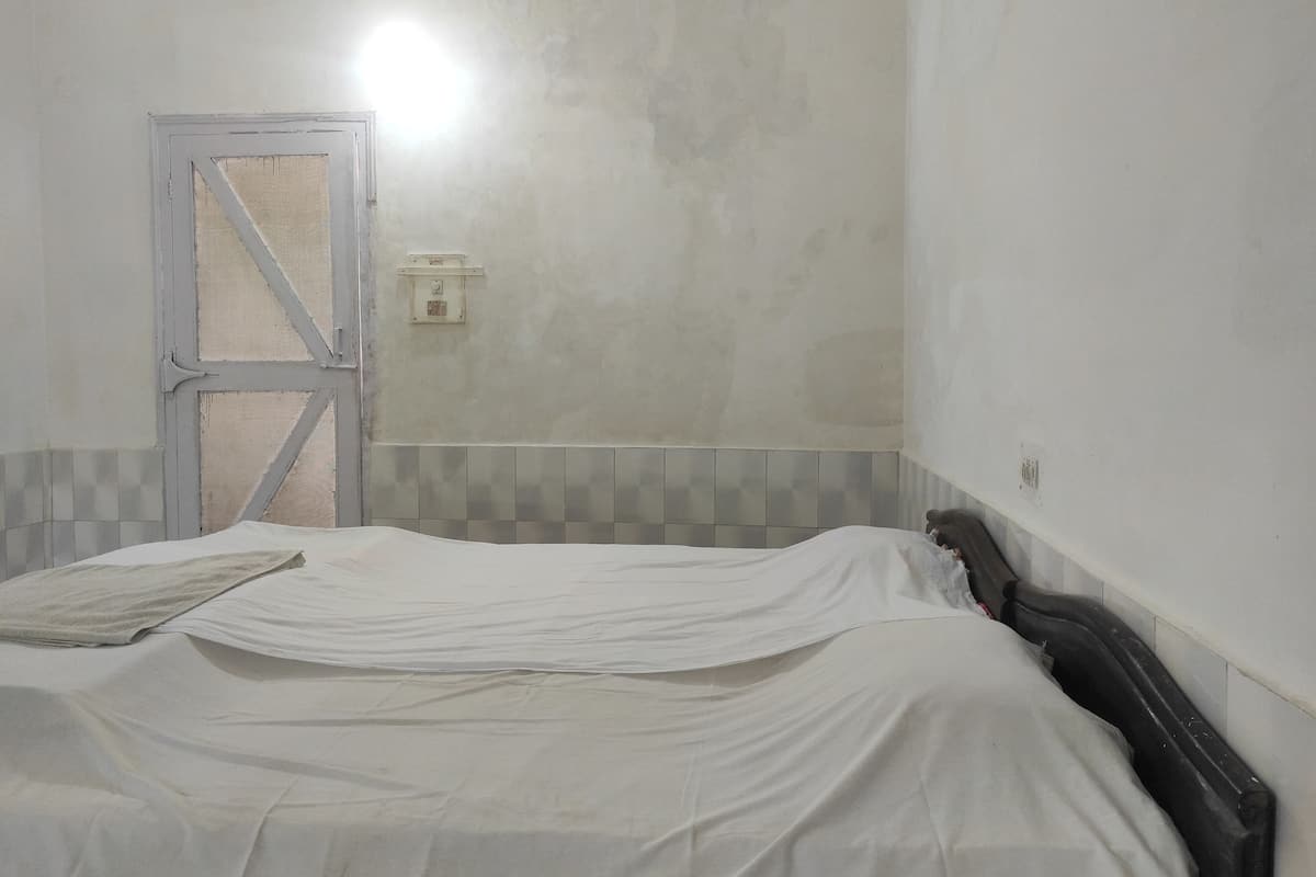 A room with a bed, a door, and a wall-mounted light fixture.