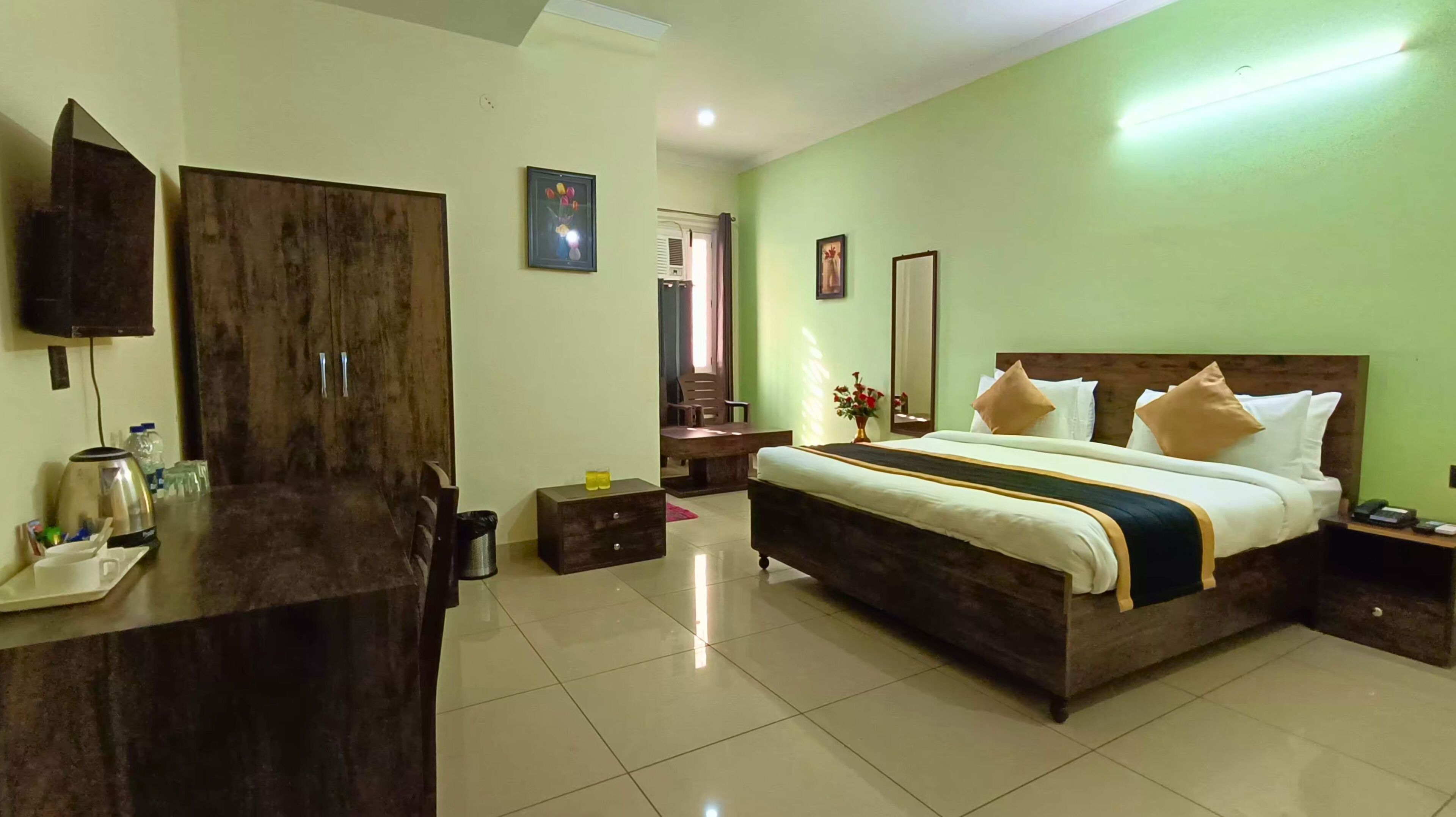 Habitación de hotel con una cama grande, un escritorio, una silla, un armario y un espejo.