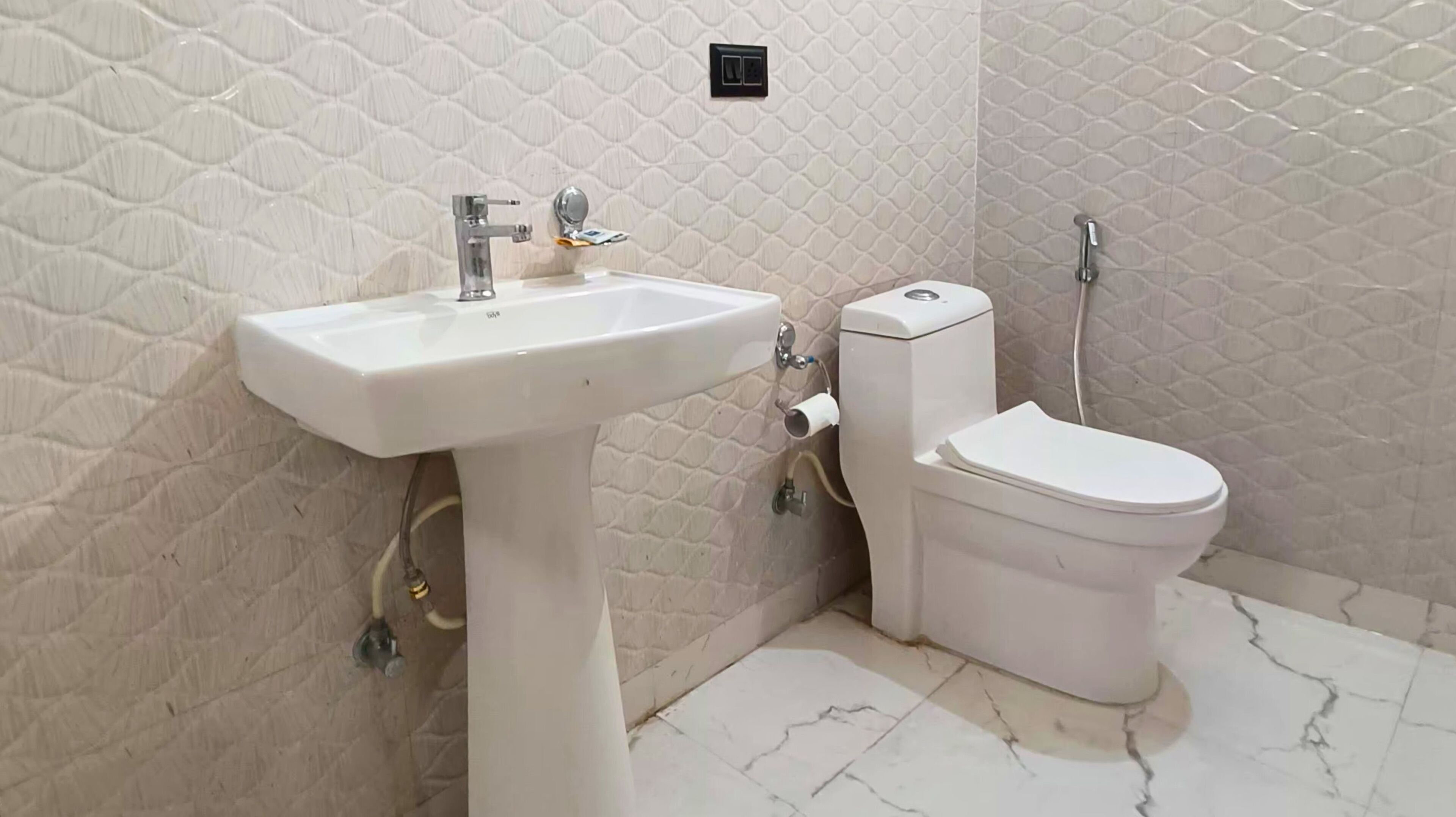 Une salle de bain avec un lavabo, des toilettes et une douche, le tout de couleur blanche.