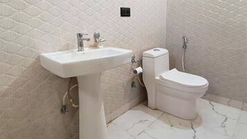 Une salle de bain avec un lavabo, des toilettes et une douche, le tout de couleur blanche.
