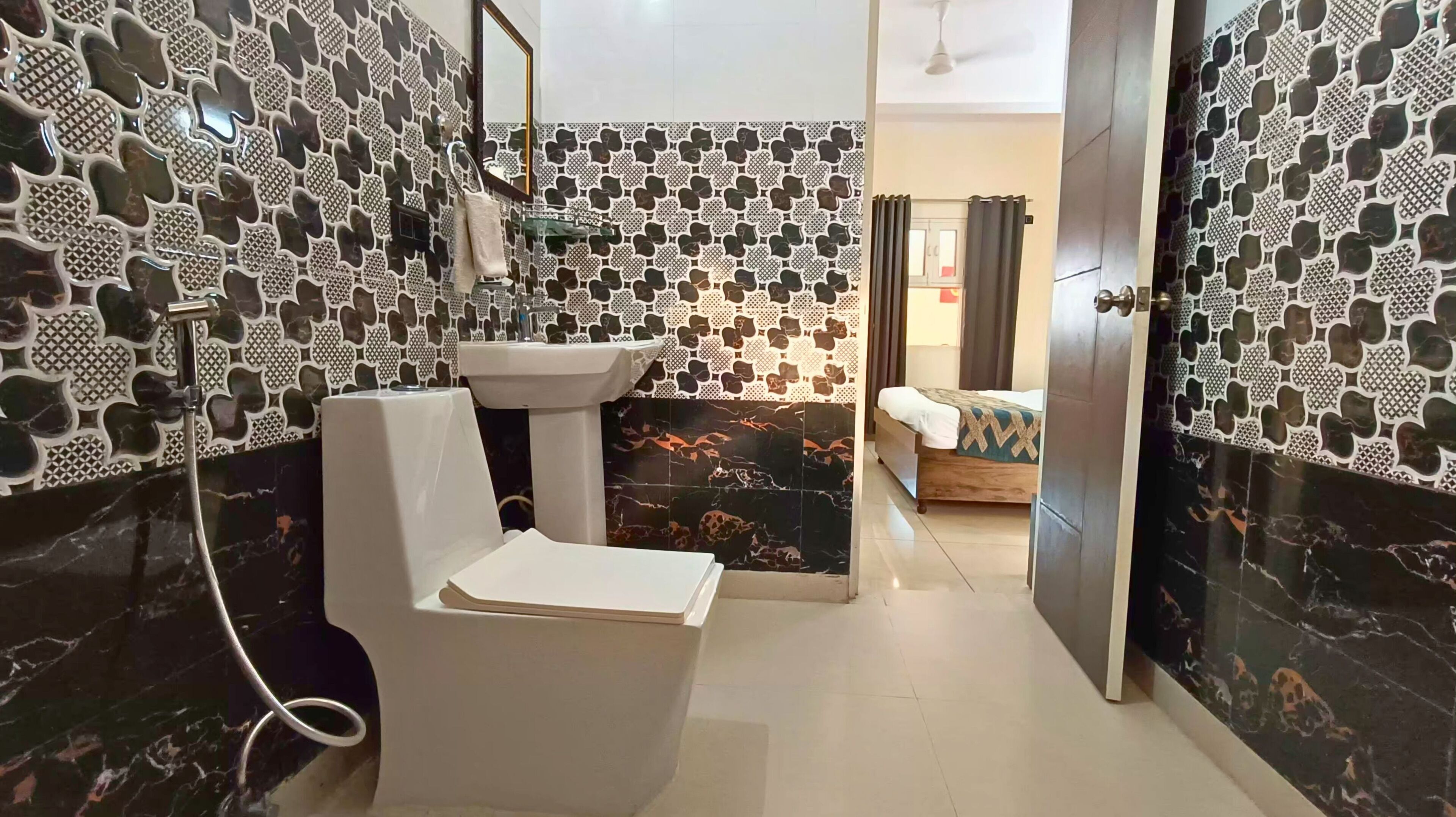 A bathroom with a toilet, sink, and shower. The walls are decorated with a patterned tile design.