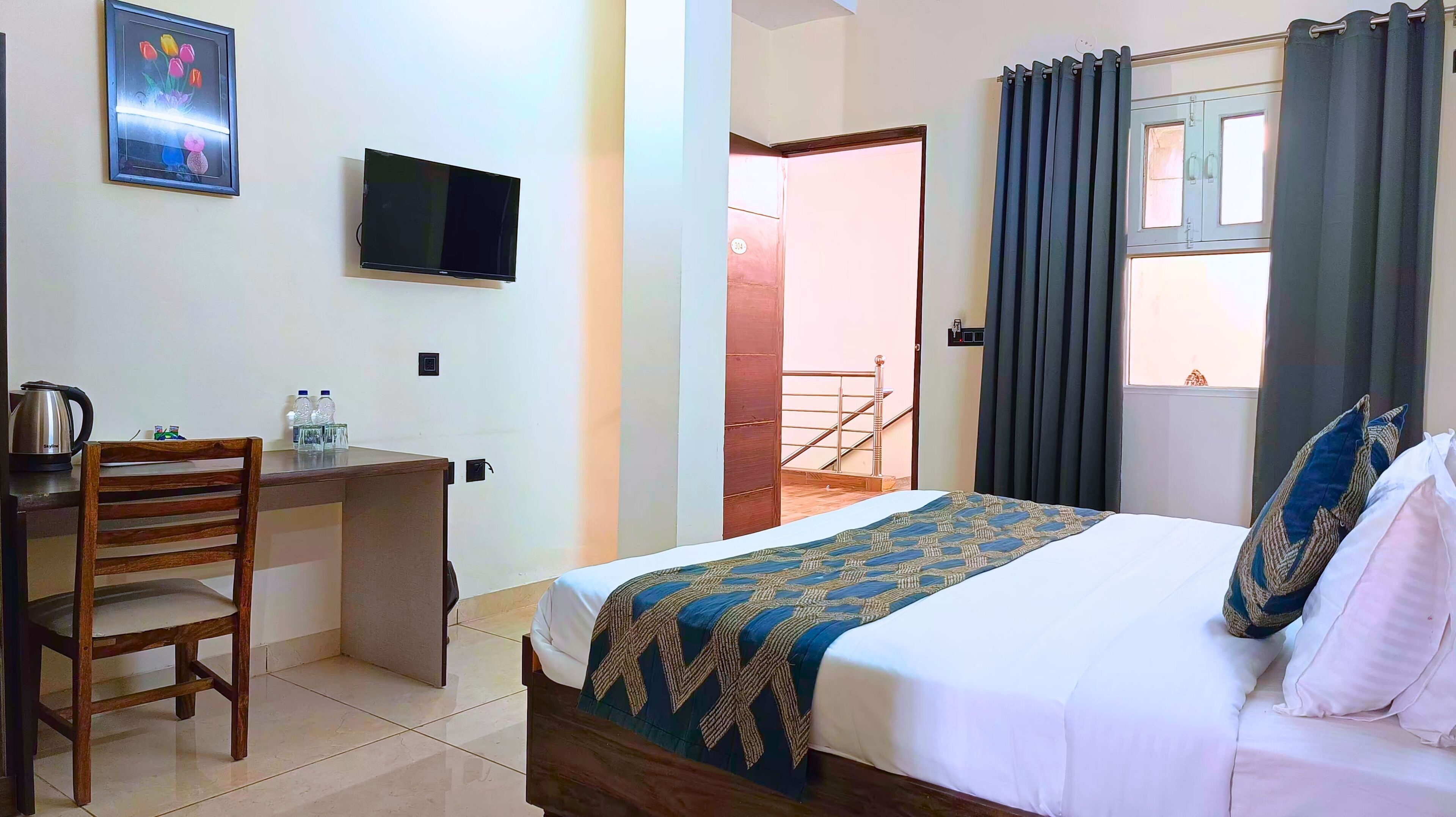 A hotel room with a bed, a desk with a chair, a television, and a view of the outside.