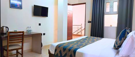 A hotel room with a bed, a desk with a chair, a television, and a view of the outside.