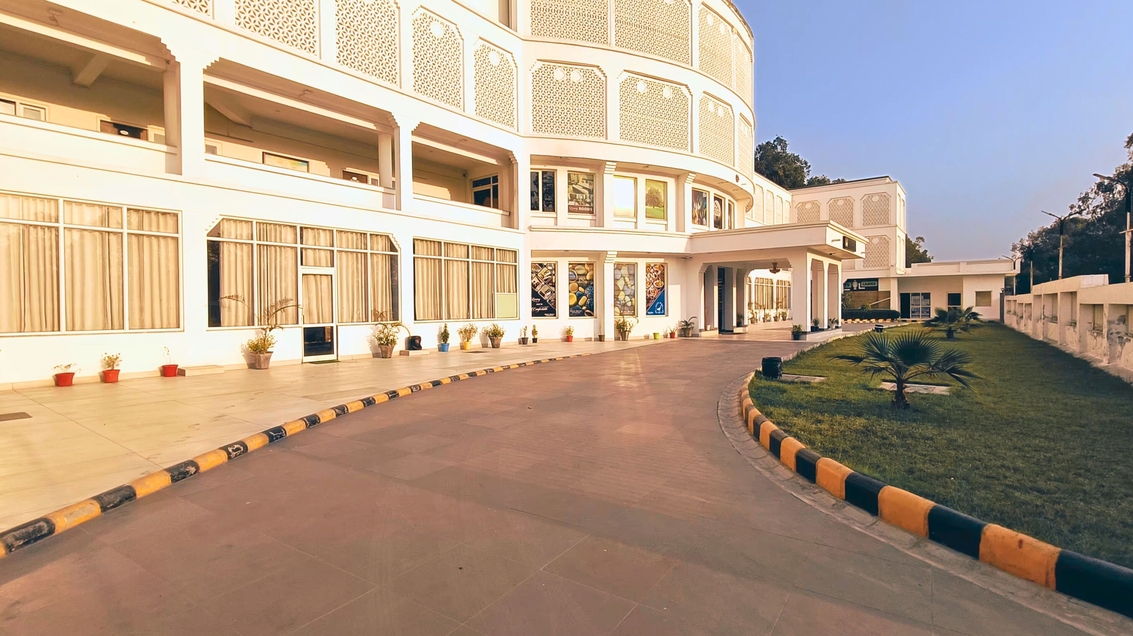 A large, multi-story building with a curved facade, multiple balconies, and a central courtyard with potted plants.