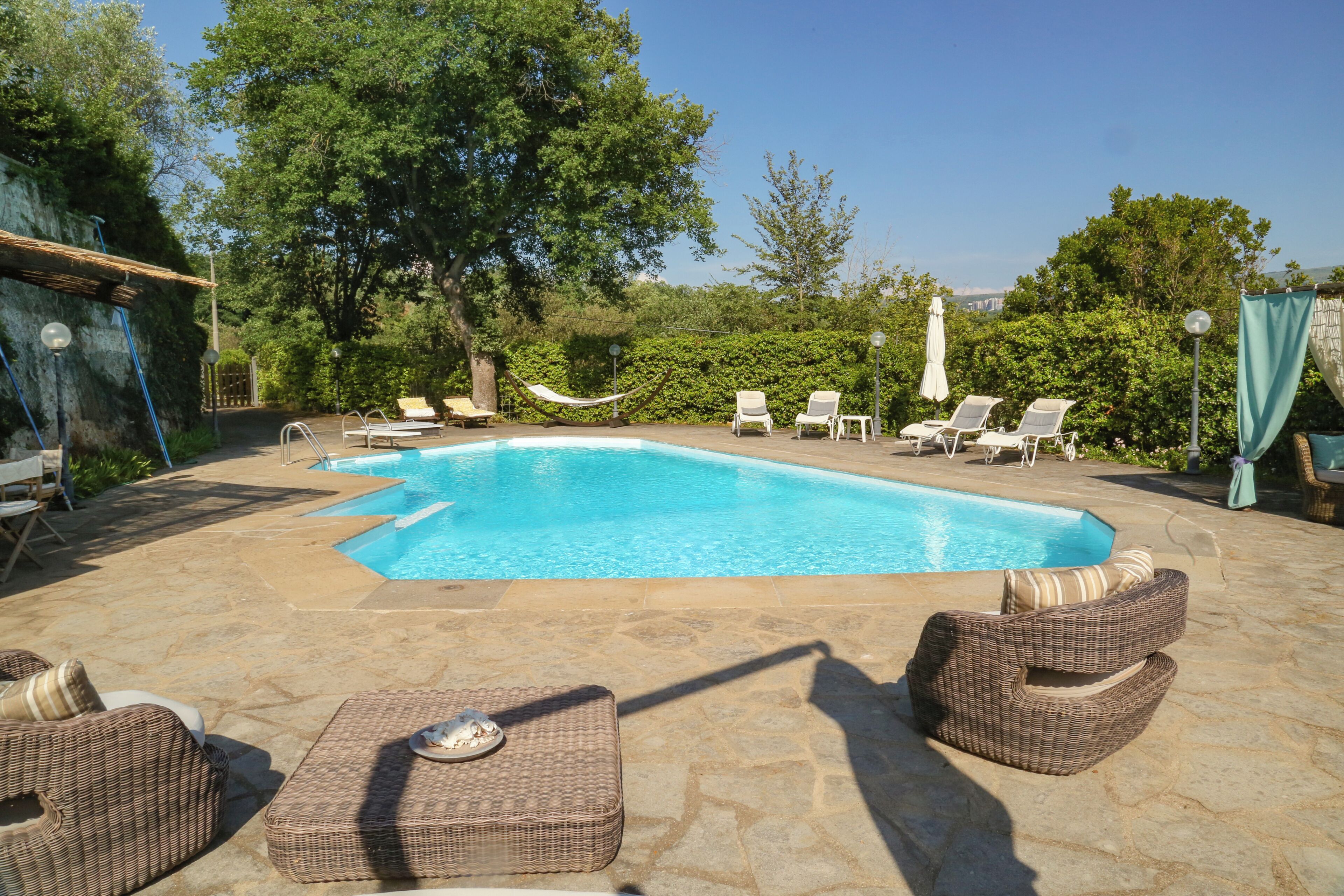 A swimming pool with lounge chairs and a hammock.