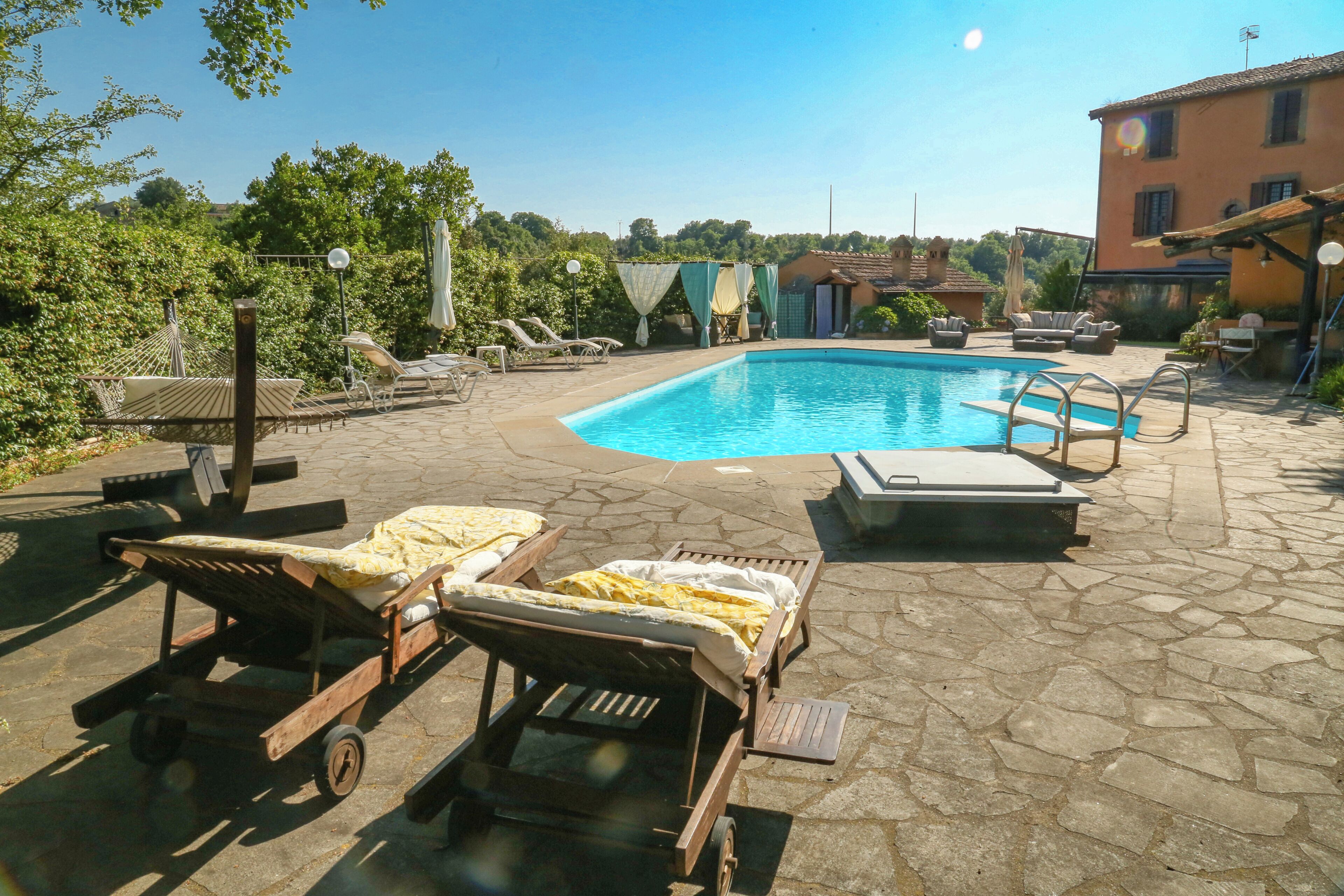 A pool area with lounge chairs, a wooden cart, and a stone patio.