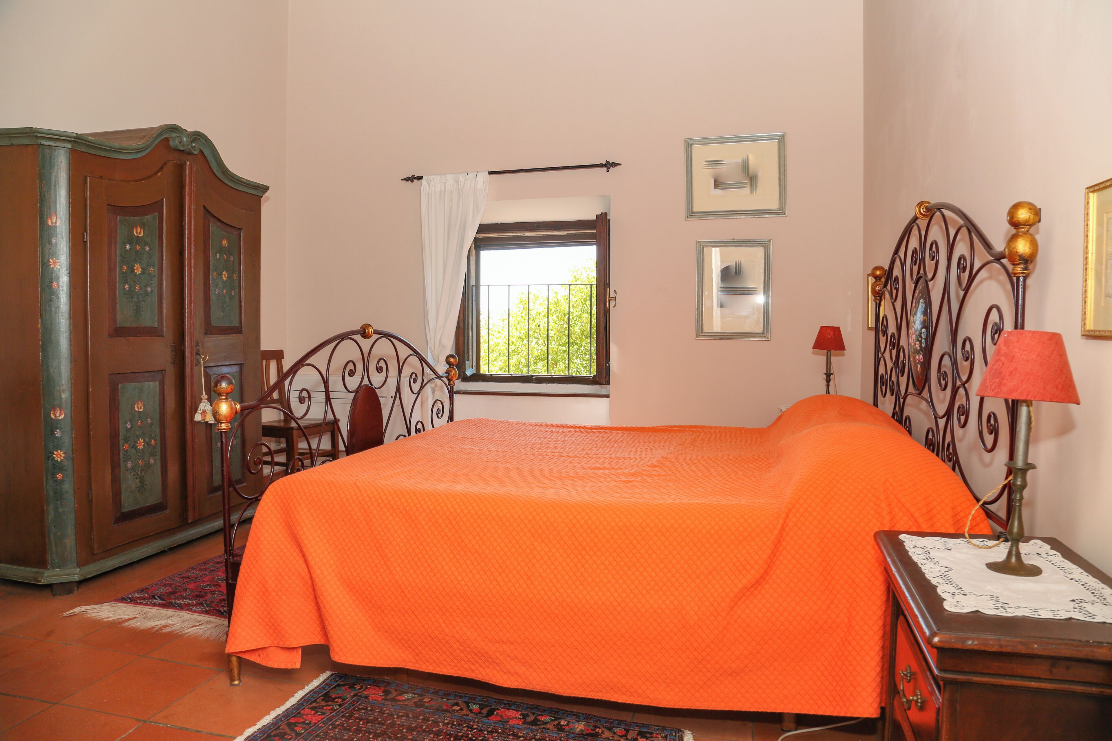 A bedroom with a bed, a wardrobe, a window, and a nightstand.
