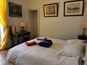 Un lit bien fait, avec des serviettes et des oreillers soigneusement pliés, une table de chevet avec une lampe et des tableaux encadrés accrochés au mur.