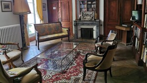 Un salon traditionnel avec une cheminée, un canapé, une table basse et une bibliothèque.