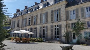 Un bâtiment historique doté d’une cour, d’un espace extérieur aménagé avec des sièges et d’un banc en pierre.