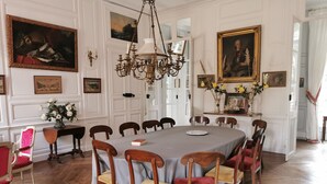 Une salle à manger élégante, avec une grande table ronde, des chaises en bois et un lustre.