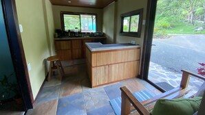Una cocina compacta con gabinetes de madera y una isla central, un taburete pequeño y un banco con cojín.