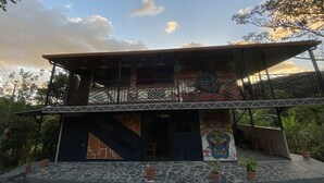 Un edificio de dos pisos con un balcón y un mural en la pared inferior.