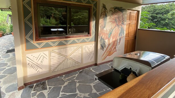 Un piso de baldosas de piedra, una ventana con marco decorativo y un mural de un águila.