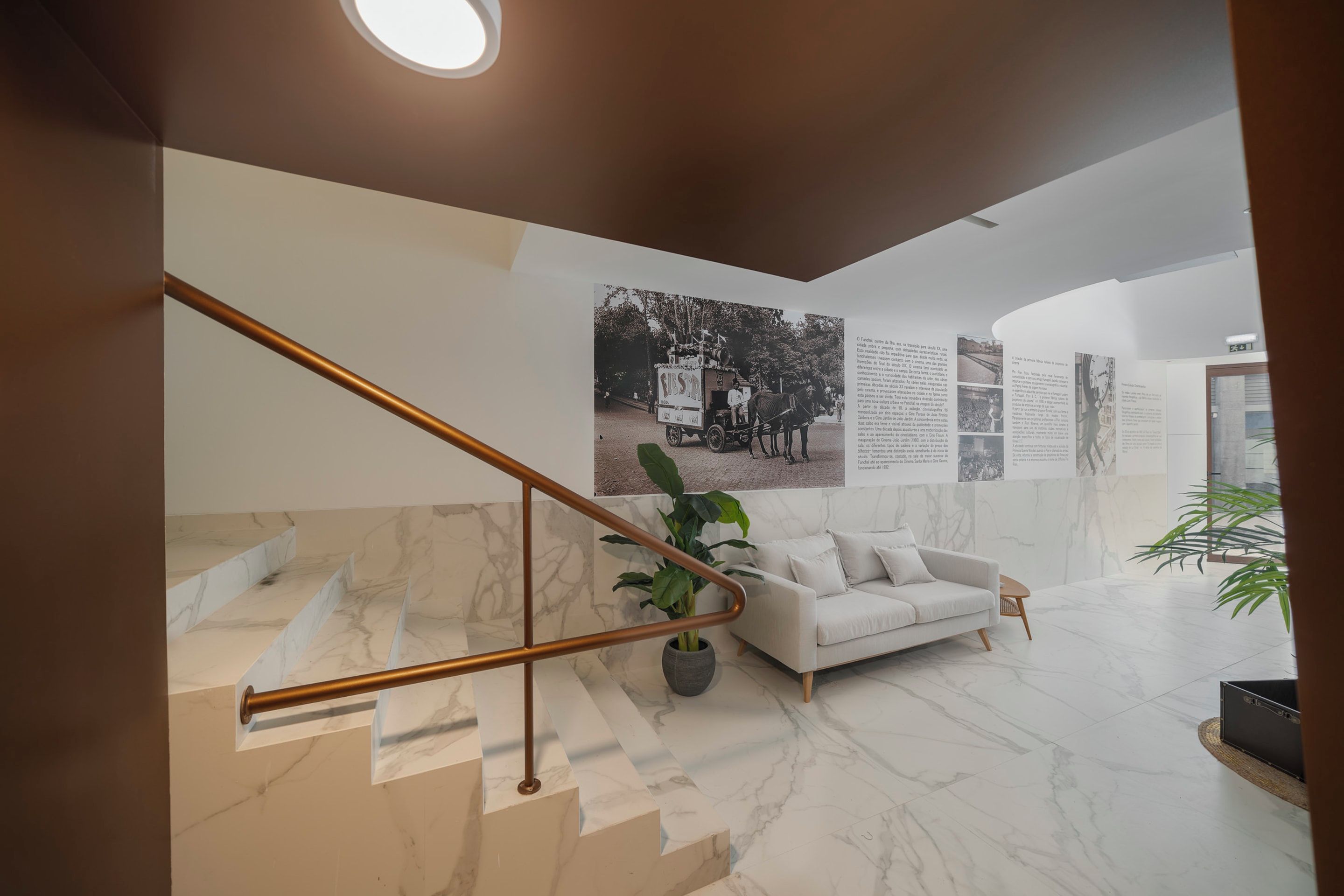 A modern interior with a marble staircase, a white sofa, and informational posters on the wall.