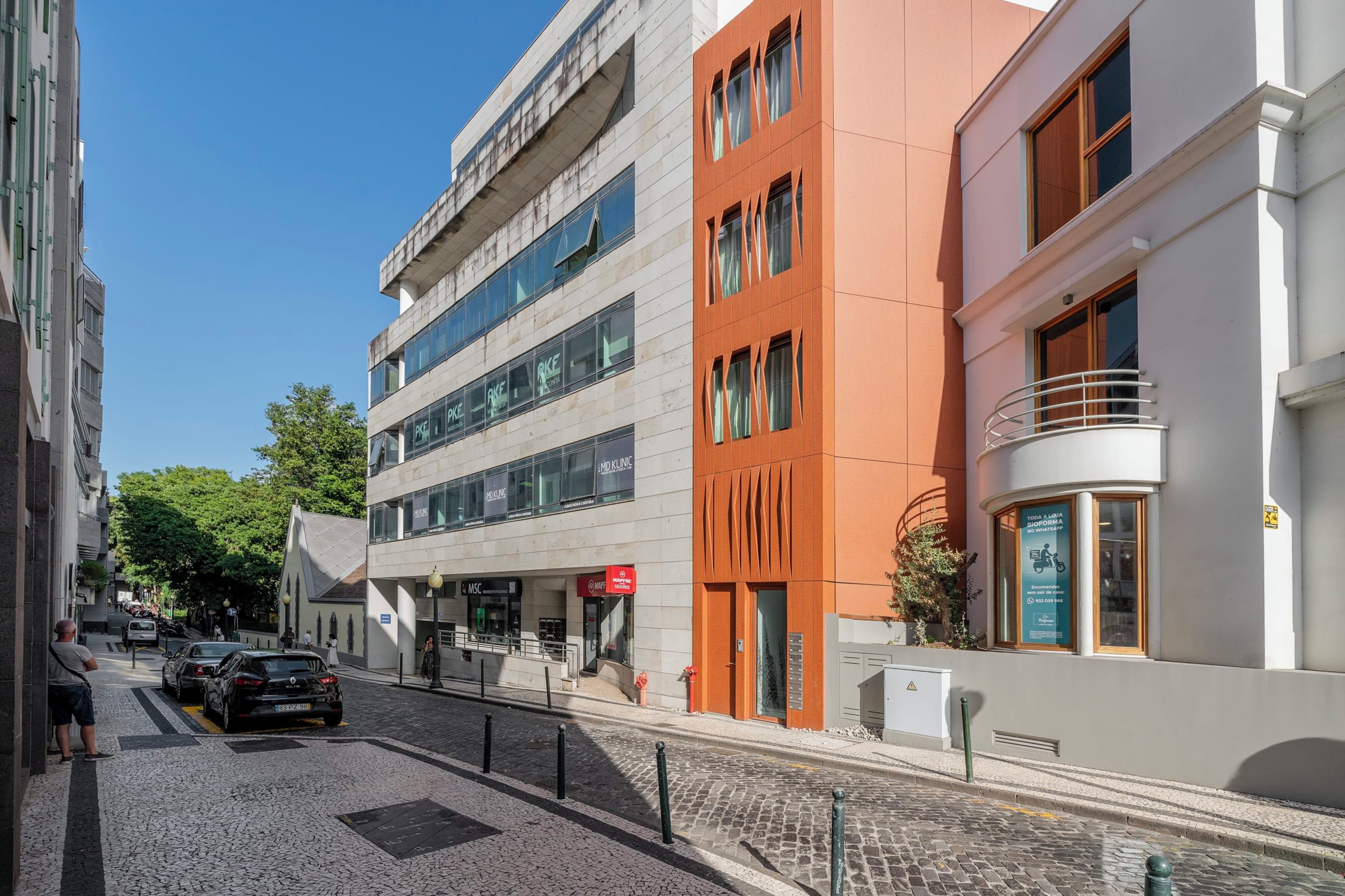 A street view with a building featuring a ground floor with a sign for a medical clinic and a pharmacy.